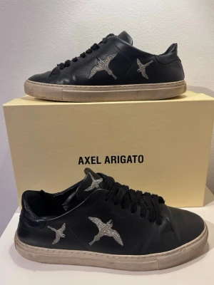 Axel Arigato Skor ”Clean 90” - Säljer ett par riktigt sjysta Axel Arigato skor i modellen ”Clean 90” med fågel tryck i storlek 42. Nypris ligger runt 2000+. Box följer med! Skriv för frågor eller funderingar! KAN GÅ NER I PRIS VID SNABB AFFÄR! 🗣️