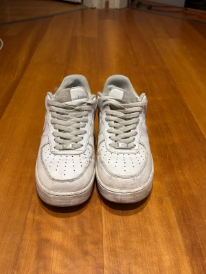 Vita låga sneakers med perforering - Säljer ett par klassiska vita sneakers med lågt skaft och perforerade detaljer på tån. Skorna har vita snören och en tjock sula. Materialet ser ut att vara läder eller konstläder. Perfekta för en clean och stilren look.