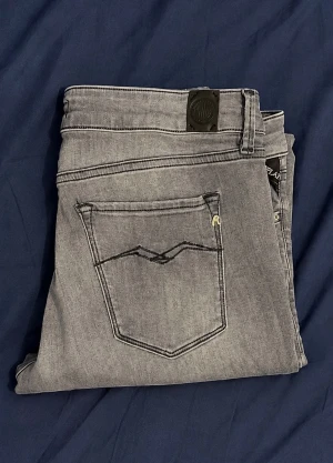 Gråa slim fit jeans - Säljer ett par gråa slim fit jeans med klassisk femficksdesign och snygga sömmar på bakfickan. Jeansen har bälteshällor och är tillverkade i ett mjukt denimtyg som ger en skön passform. Perfekta till en avslappnad stil. Kan diskutera priset 👌