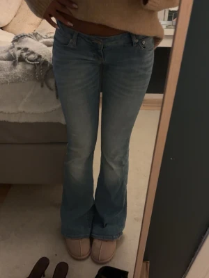 Ljusblå bootcut jeans - Säljer ett par ljusblå bootcut jeans med låg midja. Jeansen har en lätt tvättad look och utsvängda ben. Använt fåtal gånger 