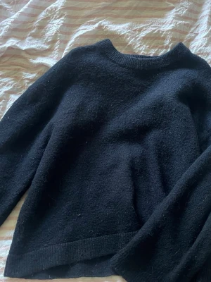 Mörkblå stickad tröja med rund hals - Mysig mörkblå stickad tröja med rund halsringning och långa ärmar. Tröjan har en enkel och klassisk design, perfekt att matcha med jeans eller kjol. Materialet ser ut att vara mjukt och lite luddigt för extra komfort.