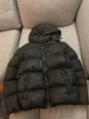 Svart pufferjacka från Tommy Hilfiger - Snygg dunjacka från Tommy Hilfiger . Perfekt för kalla vinter dagar. Bara skriva vid eventuella funderingar 