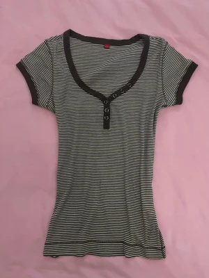 Randig ribbad henley med knappar - Snygg ribbad topp med brun och vita ränder. Korta ärmar och dekorativa knappar framtill. Bruna kanter vid hals och ärmslut ger en clean kontrast. Perfekt till jeans eller kjol för en chill look.