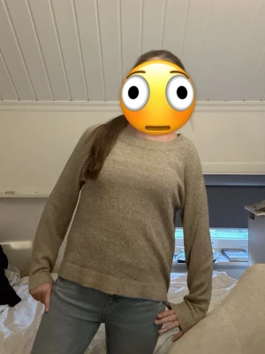Beige stickad tröja med rund hals - Mysig beige stickad tröja med rund halsringning och långa ärmar. Tröjan har en avslappnad passform och ribbstickade muddar vid ärmslut och nederkant. Perfekt för lager på lager under kyliga dagar.