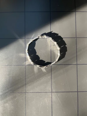 Silvrigt kantigt armband - Snyggt armband i silverfärgad metall med kantig, geometrisk design. Länkarna har en facetterad yta som reflekterar ljuset och ger ett coolt intryck. Perfekt för dig som gillar minimalistiska och moderna accessoarer.