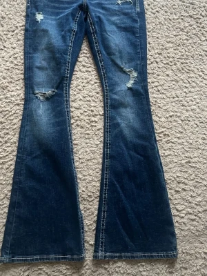 Blå bootcut jeans med slitningar - Säljer ett par mörkblå bootcut jeans med slitna detaljer ifrån Gina tricot.Perfekta för en avslappnad och trendig look. Säljer då jag aldrig använder dem! 💘