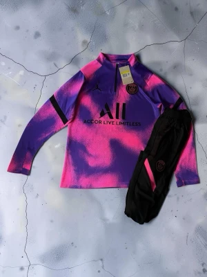 PSG träningströja och byxor lila/rosa - 🔥💜 PSG Träningsset 💜🔥  💜 Snyggt PSG-set i lila & rosa ⚽️ Stilren och unik design 👕 Långärmad träningströja med halv dragkedja 👖 Matchande träningsbyxor 🧸 Mjukt, lätt & bekvämt material 💨 Perfekt för träning och sport 🏃‍♂️ Skön passform som gör det lätt att röra sig 😎 Funkar även perfekt som en clean vardagsoutfit ✨ Riktigt snygga detaljer som sticker ut  📏 Storlek: (M) 💯 Skick: Nytt med tags 📦 Setet innehåller tröja + byxor  💸 Pris: (600kr) 📩 DM vid intresse eller frågor  🚨 