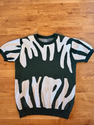 Grön kortärmad topp med vit zebra - Cool grön topp med korta ärmar och ett iögonfallande vitt zebramönster. Perfekt för dig som gillar statement-plagg och vill ha något annorlunda i garderoben.