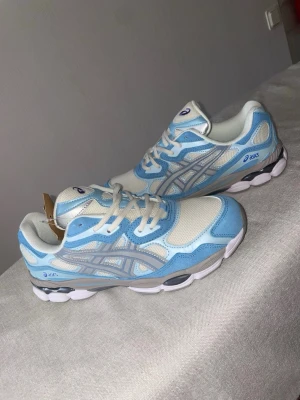 Asics sneakers i blått och vitt - Snygga sneakers från Asics i en fräsch kombination av ljusblått och vitt med grå detaljer. Ovandelen är i mesh och syntet för bra andningsförmåga och komfort. Klassisk snörning och sportig vibe som passar perfekt till streetwear.