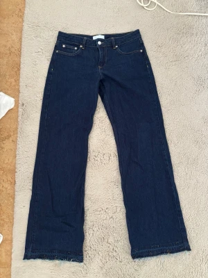 Mörkblå raka jeans från NAKD - Mörkblå raka jeans med låg midja från NAKD. De är uppsprättade längst ner men går att sy upp om man vill.