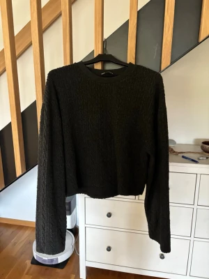 Svart kabelstickad tröja från Zara - Snygg svart kabelstickad tröja från Zara med rund halsringning och långa ärmar. Tröjan har ett klassiskt flätmönster och ribbade muddar vid halsen. Lite kortare modell
