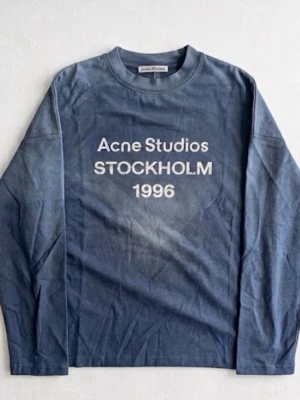 Blå långärmad topp Acne Studios - Cool långärmad topp från Acne Studios i en tvättad blå färg med tryck 'Acne Studios STOCKHOLM 1996' på bröstet. Rund halsringning och relaxed fit, perfekt för en avslappnad stil.