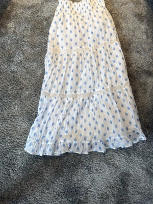 Vit långkjol med blått mönster - Säljer en vit långkjol med blå blommigt mönster från gina trickot.