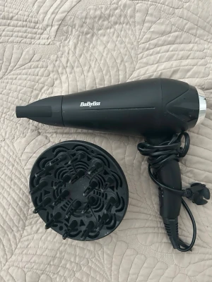 Svart hårfön från BaByliss - Säljer en svart hårfön från BaByliss med tillhörande diffuser. Hårfönen har en stilren matt finish och silverdetalj baktill. Passar perfekt för styling och torkning av håret. Elektrisk med sladd och EU-kontakt.