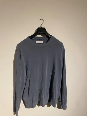 Blå basic tröja med rund hals - En stilren blå tröja från Samsøe samsøe med rund halsringning och långa ärmar. Tröjan har ribbade muddar vid ärmslut och nederkant, perfekt för en enkel och clean look. Passar till det mesta och är lätt att matcha med andra plagg. Nypris 1200kr