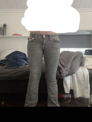 Grå bootcut jeans med fickor - Snygga grå jeans med bootcut-modell och klassiska fem fickor. Jeansen har silverfärgade knappar och detaljer på bakfickorna. Tillverkade i denim med en lätt tvättad look som ger en cool vibe.
