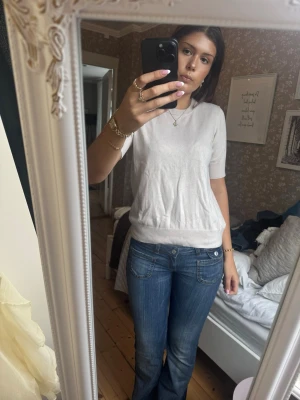 Vit kortärmad topp - Vit topp med rund hals och korta ärmar. Modellen har ribbade muddar vid ärmslut och nederkant för en clean look. Tillverkad i mjukt material som känns skön mot huden. Enkel att styla till olika outfits.