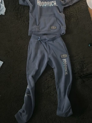 Blått Hoodrich set med  - Storlek S om du vill köpa bara hoodien eller bara byxorna om du vill då kostar hoodien 250kr och byxorna 150kr men båda 2 är 350kr                                                      Säljer ett blått Hoodrich set med hoodie och matchande byxor. Hoodien har stor ficka framtill, tryckt logga på bröstet och blått innerfoder i huvan. Byxorna har tryckt logga på benet och resår i midjan. Perfekt för en chill och avslappnad stil. 