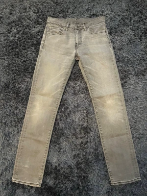 Grå Levi's 511 slim jeans - Säljer ett par gråa Levi's 511 slim jeans med klassisk femficksdesign och dragkedjegylf. Jeansen har en snygg tvättad look och är tillverkade i ett mjukt denimtyg som sitter tajt över benen. Perfekta för dig som gillar en modern och stilren stil. Storlek 28 W och 32 L. Skriv till mig om du har några frågor.