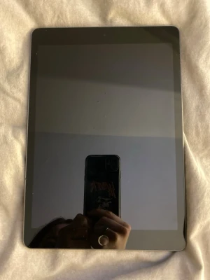 Ipad 9e generationen ifrån 2021 64gb - Säljer en Apple iPad med svart framsida och baksida i rymdgrå aluminium. Platt och tunn design med rundade hörn och stor pekskärm. Perfekt för surf, appar och streaming. Klassisk Apple-logga på baksidan.