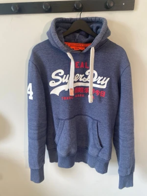 Superdry Hoodie - Tja! Säljer en fet hoodie från Superdry i mycket fint skick. Tröjan är i Storlek S men passar mer som M. Tröjan är aldrig använd förutom när jag tog bilderna i annonsen. Modellen i bilderna är 185-186. Hör av er vid ev frågor!