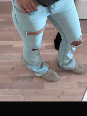Ljusblå slitna bootcut jeans - Säljer ett par ljusblå bootcut jeans från nelly. Passar mig som är 176cm lång. Jeansen har klassisk femficksdesign och är tillverkade i denim med en avslappnad passform. Perfekta för en trendig och avslappnad look.