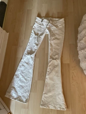 Går ej att köpa längre då de är tingade❣️ - Säljer ett par vita jeans med utsvängda ben och snygg spetsdetalj på bakfickan. Jeansen har normal midja och klassisk femficksmodell. Perfekta för dig som vill sticka ut med en retrovibe och gillar detaljer.
