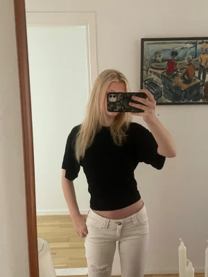 Svart croppad topp med kort ärm - Säljer en svart croppad topp med korta ärmar och rund hals. Toppen har en slim passform och är perfekt till jeans eller kjol. Materialet känns mjukt och stretchigt, troligen bomull eller polyester.