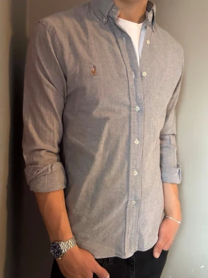 Ralph Lauren skjorta grå – M slim fit -  Säljer denna stilrena och snygga grå Ralph Lauren skjorta. Skjortan är i mycket bra skick och storlek M slim fit. Perfekt för både vardag och mer uppklädda tillfällen. Har du några frågor? Tveka inte att höra av dig. Allt gott från Deluxe Garderoben ⭐️