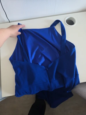 Blå långklänning med slits - Snygg blå långklänning med smala axelband och hög slits framtill. Klänningen har en figurnära passform och är tillverkad i ett mjukt, stretchigt material som ger en elegant siluett. Perfekt för dig som vill sticka ut med en färgstark look.
