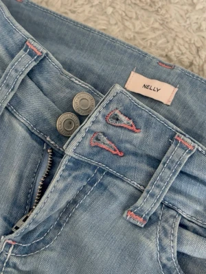 Nelly jeans  - Blåa jeans ifrån Nelly, HELT oanvända. Ingen fläck inget hål ingenting inte ens använda❣️ Rosa detaljer och 2 knappar fram. Säljs pågrund av att dom är för långa, så skulle rekommendera dessa för långa tjejer!!