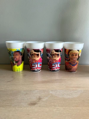 Fyra plastmuggar med sportmotiv - Säljer fyra färgglada McDonalds FIFA World cup plastmuggar. INGA MUGGAR ANVÄNDA! . Motiven inkluderar fotbollsspelare och amerikanska fotbollsspelare i olika färger, bland annat gult, rött och blått. Perfekta till kalas eller som samlarprylar. 