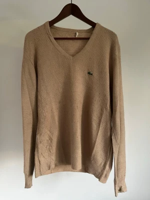 Vintage Lacoste V-ringad Stickad Tröja Beige Soft Orlon Akryl Herr M - Vintage Lacoste V-ringad Stickad Tröja Beige Soft Orlon Akryl Herr M Storlek: M Färg: Beige / Sand Passform: Regular fit  Krage: V-ringad (V-neck) Material: 100% Akryl Skick: Denna tröja är i ett väldigt fint skick utan defekter  Nypris cirka: 1 500 kr