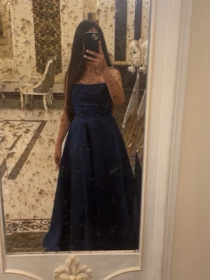 Marinblå axelbandslös långklänning - Elegant marinblå långklänning med axelbandslös design och draperad överdel. Perfekt för bal eller festliga tillfällen. Använd en gång i någon timme