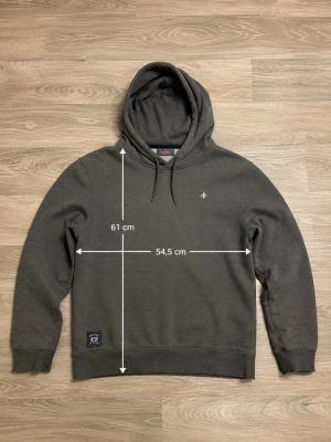 Grå hoodie från Morris Stockholm - Snygg grå hoodie från Morris Stockholm i storlek S. Hoodien har dragsko i huvan, broderad logga på bröstet och patch nertill. Mjuk insida och klassisk passform, perfekt för en chill och stilren look. Barnstorlek! 