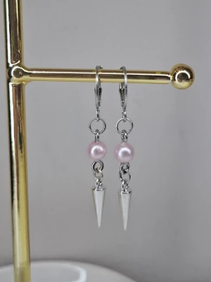 Silvriga örhängen med rosa pärlor - Snygga örhängen i silverfärgad metall med ljusrosa pärlor och spetsiga konformade hängen. Perfekta för dig som gillar en mix av sött och edgy stil. Lätta att bära och ger en cool touch till din look. Ej rostfria