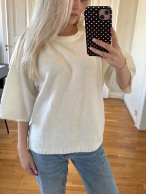 Vit stickad tröja med vida ärmar - Säljer en enkel och stilren vit stickad tröja med rund halsringning och trekvartsvida ärmar. Tröjan har en rak passform och ribbade kanter nedtill. Perfekt att matcha med jeans för en avslappnad look❤️. Skriv för mer info