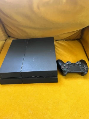 PlayStation 4 spelkonsol med handkontroll - Säljer en svart PlayStation 4 spelkonsol tillsammans med en matchande svart handkontroll. Konsolen har en stilren, rektangulär design i plast och passar perfekt för gaming och underhållning hemma.