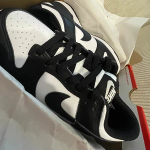 Nike Dunk Low Panda svart/vit - Nike Dunk Low Panda i svart och vitt skinn med klassisk Swoosh-logga på sidorna. Lågt skaft, svart snörning och vit perforerad tå. Snygg kontrast mellan färgerna och en ikonisk siluett som passar till streetwear. 
