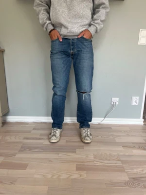Levi's 501 W32 – Vintage fade | Distressed knä | Straight fit - LEVI’S 501 ORIGINAL  Storlek: W32 (längd svårläst på lappen — mät gärna innebenslängden) Passform: Straight fit, hög midja Färg: Mediumblå med naturlig vintage fade Material: 100% bomull.                                   Klassiska 501:or med åldrad läderplatta och fin naturlig fading — den typ av tvätt som bara kommer med åren. Knappgylf och orangea nitar som det ska vara.  Modellen på bilden är 175 cm och väger 65 kg. Skick: Bra vintage-skick. Nypris: ca 1 299 SEK
