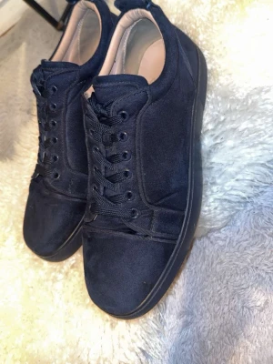 Mörkblåa sneakers i mocka - Snygga mörkblå sneakers i mocka med matchande mörkblå snören och sula. Skorna har en klassisk låg profil och stilren design, perfekt för dig som gillar en clean look. Insidan är ljusbeige och ger en schysst kontrast till utsidan.