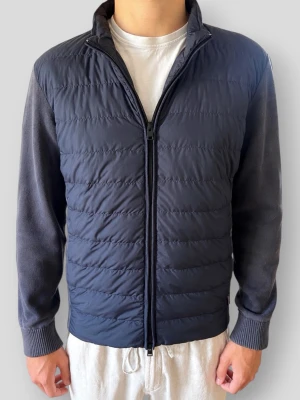 Woolrich Bomber Cardigan - Woolrich Bomber Cardigan | Modell: Hybrid Bomber Jacket | Färg: Marinblå (Navy) | Material: Mjuk premium bomull (100%) med vindavvisande, lätt fodrad framsida | Skick: Fint skick i övrigt men det stickade tyget på ärmar/axlar har blivit lite solblekt men inget man tänker på (se bilder) | Nypris: 3999 kr | Storlek: M (Normal i storleken / True to size) | Hör av dig vid minsta fundering 📦