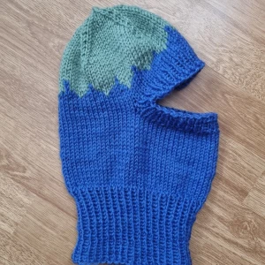 stickad blåbär balaklava - Stickad balaklava blåbär. Perfekt för kalla dagar och vinteraktivitet. Mjuk och stretchig passform, öppning för ansiktet. Material 100% akryl. Unisex, passar äldre barn eller vuxen huvudmått 54 - 57 cm