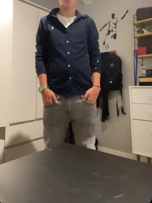 Polo Ralph lauren skjorta - Säljer en stilren mörkblå polo skjorta med klassisk krage och vita knappar. Skjortan har lång ärm och är tillverkad i ett mjukt bomullstyg. Perfekt för dig som vill ha en enkel men snygg look. Inga defekter på skjortan och pris kan diskuteras!