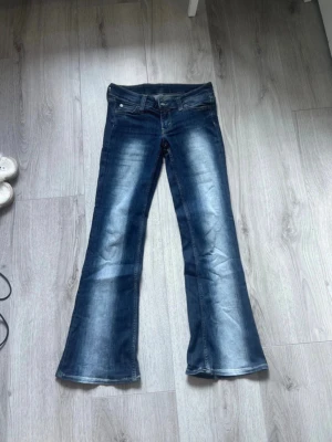 Blå bootcut jeans  - Säljer ett par blå bootcut jeans från weekday. Jeansen har klassisk femficksdesign och är tillverkade i denim. Perfekta för dig som gillar en retroinspirerad look med utsvängda ben.