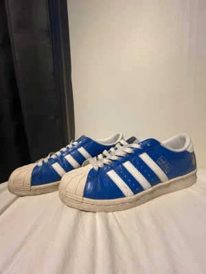 BABE x Adidas Superstar - Säljer nu dessa super snygga Superstar skorna som är en collab mellan BAPE och Adidas.  Dom är i storlek 45 1/3 men skulle säga att  de passar mer som storlek 44. Dom är svåra att få tag på och har därmed ett högre pris.  Det är i bra skick men sulorna e nägot slitna fram och baktill men inte mycket samt att en av skorna har ett litet hål i sulan (bild 4 och 5) men det är inget som märks av vid användning! Innersulan är i bra skick och dom är inte särkilt ingångna.  Hör gärna av dig vid frågor!