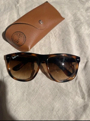 Ray-Ban bruna Boyfriend solglasögon - Säljer ett par klassiska Ray-Ban Boyfriend solglasögon i brunmelerad plast med mörktonade glas. Modellen är RB4147 och bågarna har en snygg sköldpaddsmönstrad look. Kommer med original Ray-Ban fodral i brunt skinn.