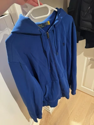 Blå hoodie från Polo Ralph Lauren - Säljer en riktigt snygg ralph lauren hoodie. Skicket är bra utan några tecken på användning i strl L. Bara att skriva vid minsta lilla