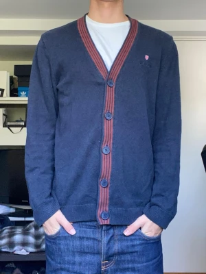 Bondelid cardigan - En riktigt snygg cardigan i marinblå färg med röda detaljer från bondelid i storlek M. Tröjan är i gott skick utan några defekter. Han på bilderna är 179 cm. Har du några frågor? Fråga på