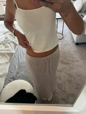 Beige ribbad långkjol - Mysig beige långkjol i ribbat material med hög midja och rak passform. Kjolen är enkel och stilren, perfekt att matcha med olika toppar för en avslappnad look.